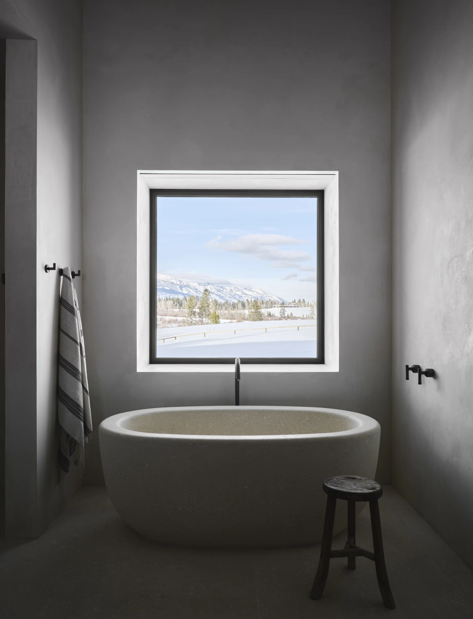 Stone tub in a quiet bathroom with window light and precise wall finishes