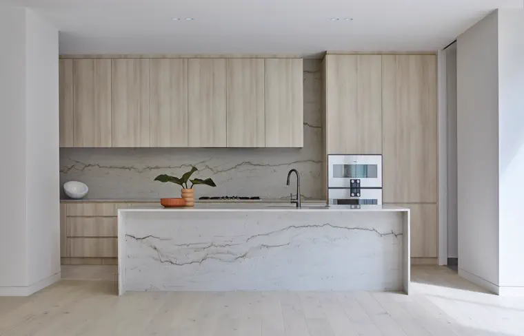 Bright kitchen with stone island, warm wood, and open living space