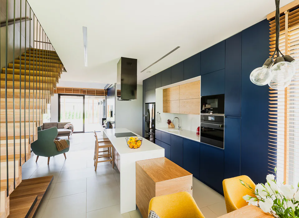 Warm kitchen remodel with dark cabinetry, wood details, and open stairs